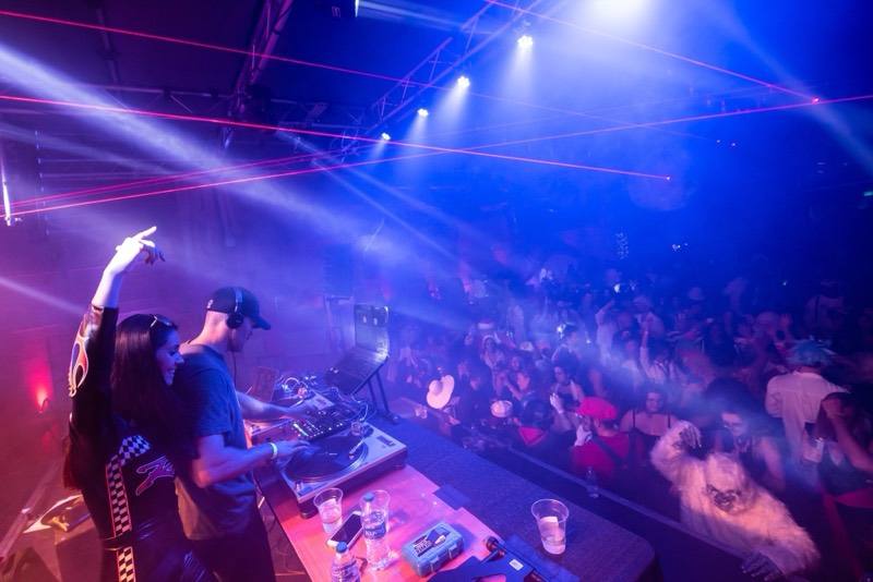 DJ throws hands up as lasers rake the fog over the dance floor on the dance floor at Coloween 2019