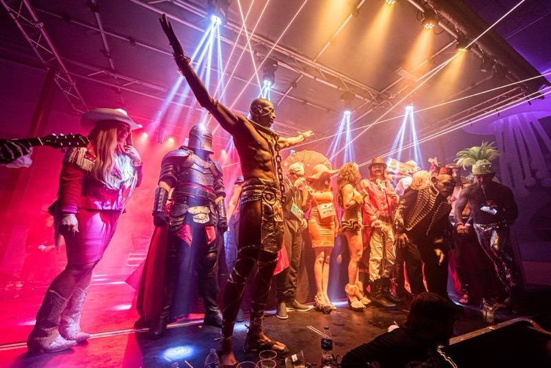 Knight, golden pharaoh, and cowgirl commanding the costume-contest stage