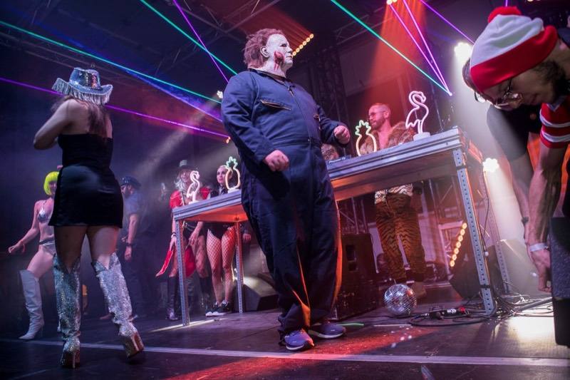 Masked slasher stalks the stage past disco cowgirls and neon flamingos at Denver's Coloween Halloween party