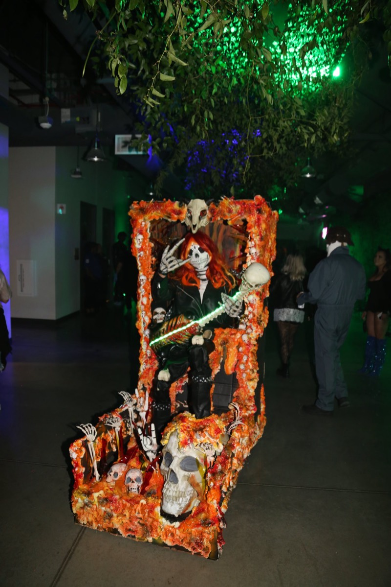 Skeleton shredding a glowing guitar on a flaming skull throne at Coloween, Denver's 21+ Halloween party