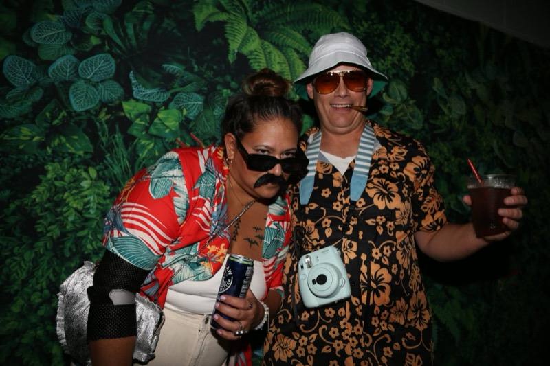 Bucket hat and tinted shades pose at the leafy photo wall at the adults-only Coloween Halloween event