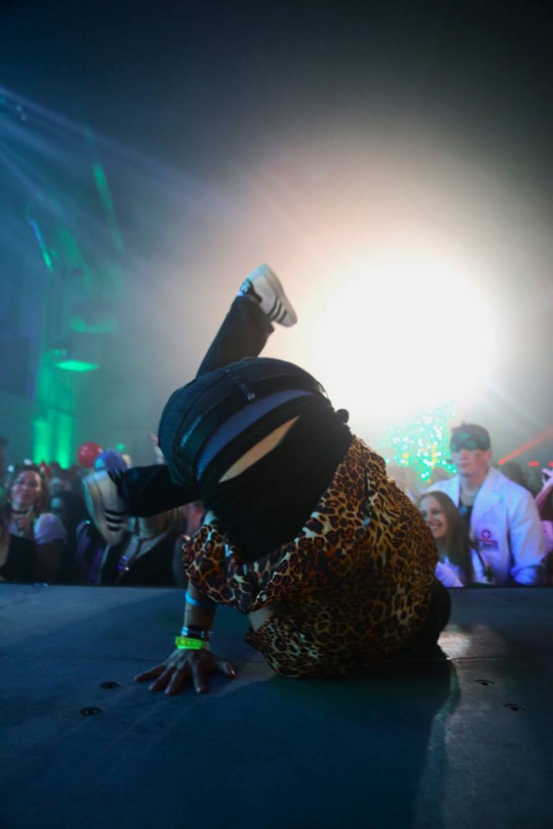 Leopard-print breakdancer frozen upside down on stage in the spotlight