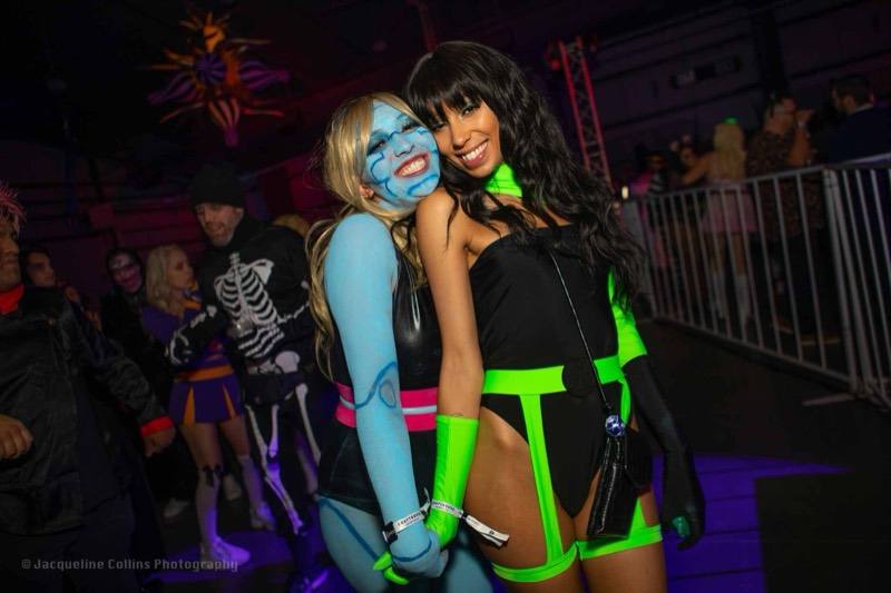 Blue body paint meets a neon green villain in a laughing hug at Colorado's biggest adult Halloween party