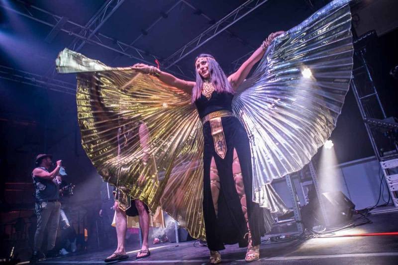 Cleopatra spreads pleated gold and silver wings across the stage at Denver's Coloween Halloween party